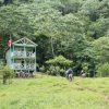 Un groupe de personnes faisant de la randonnée et se baignant près d’une petite maison à flanc de colline.